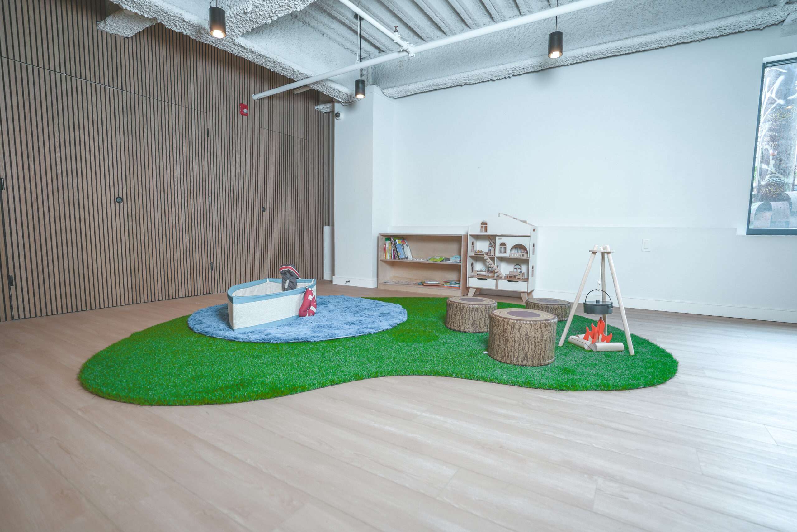 Montessori inspired playspace at Recess with a turf island and wood slat wall